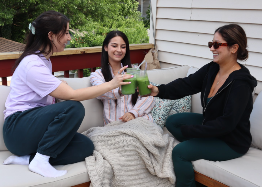 Three women sitting on a patio with a blanket, drinking molly's matcha and chatting.